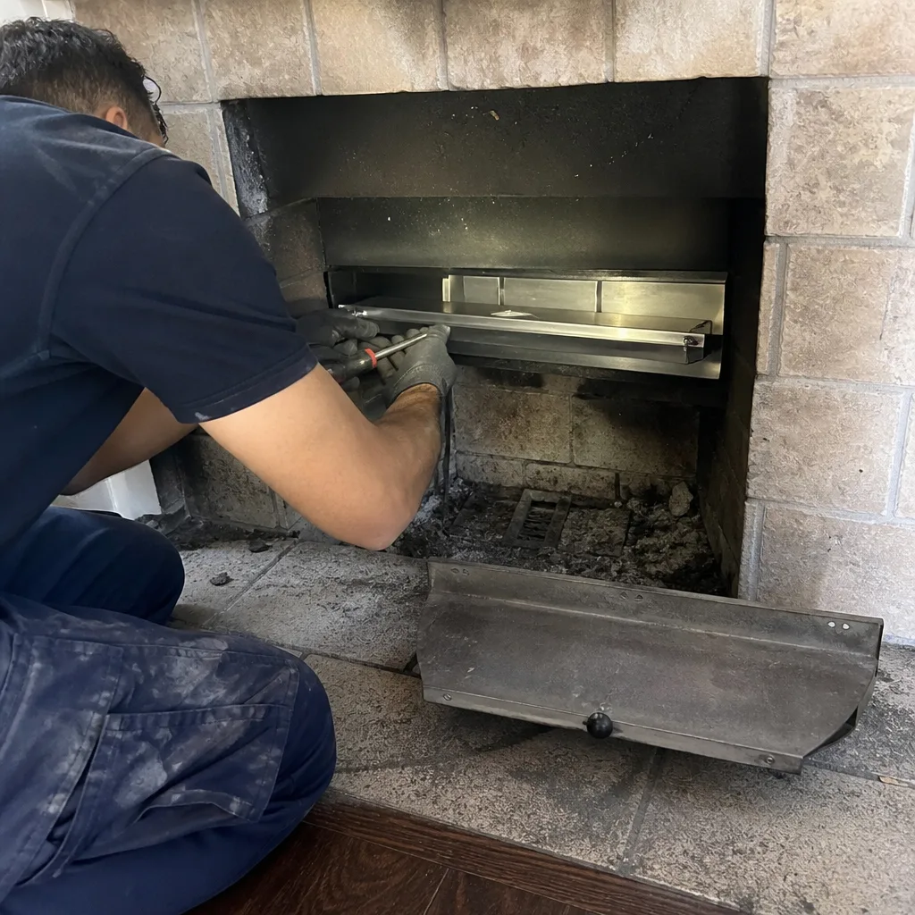 Professional chimney technician servicing and cleaning an indoor fireplace insert